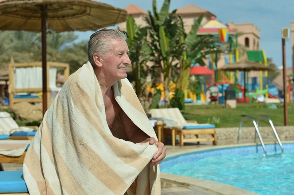 Homme âgé assis près de la piscine — Photo