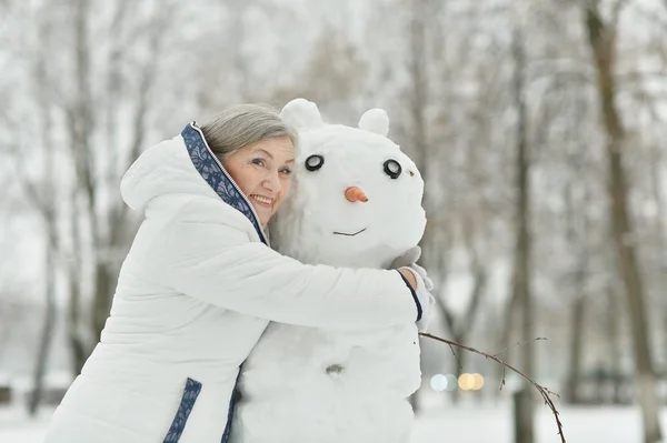 Gammal kvinna med snögubbe — Stockfoto