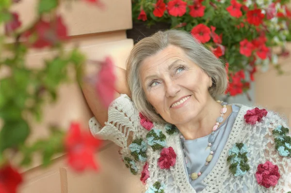 Äldre kvinna med röda blommor — Stockfoto