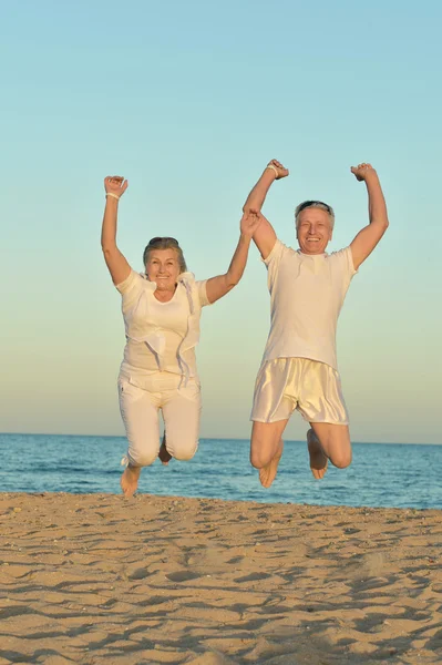 Ältere Paare springen am Strand — Stockfoto