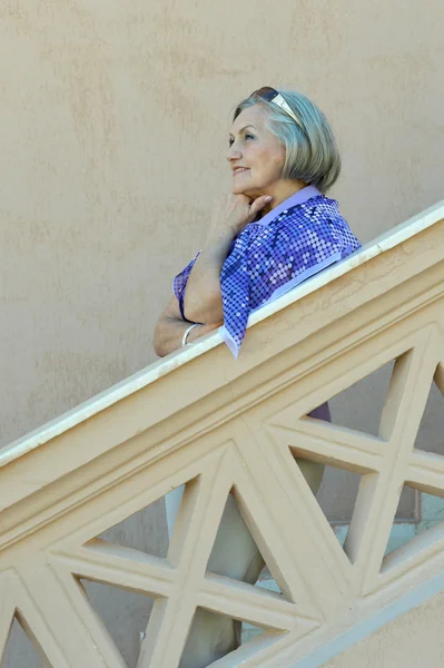 Beautiful elderly woman on stairs — Stock Photo, Image