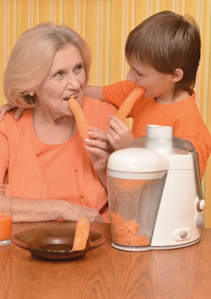 Kobieta i wnuk jedzenie marchew — Zdjęcie stockowe
