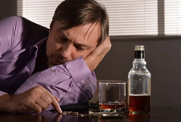 Un homme boit du whisky à table — Photo