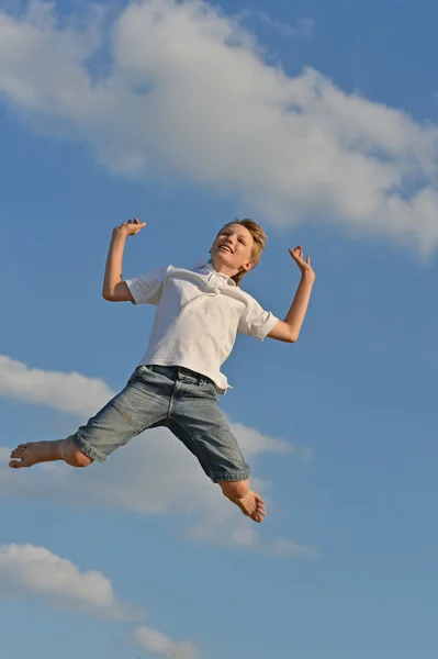 Ativo menino pulando no céu azul — Fotografia de Stock