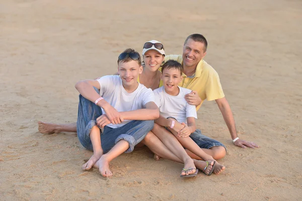 Família feliz sentada na praia — Fotografia de Stock