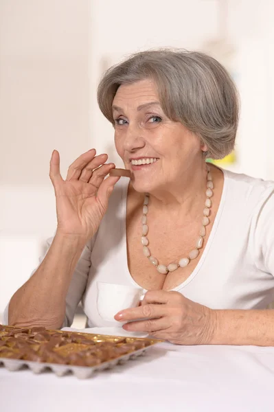 Seniorin isst Schokoladenbonbons — Stockfoto