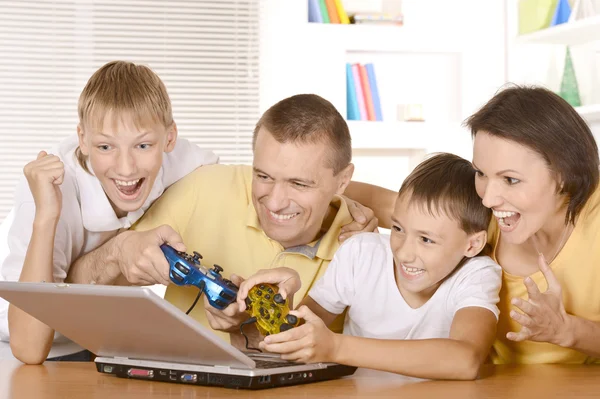 Familia jugando en el ordenador portátil en la mesa —  Fotos de Stock