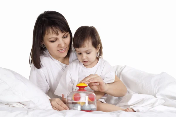 Flicka med mamma spela i sängen — Stockfoto