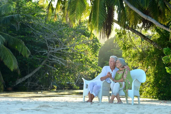 Elderly couple sitting near palm trees
