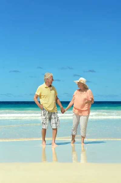 Elderly couple walking along  seashore — Stock Photo, Image