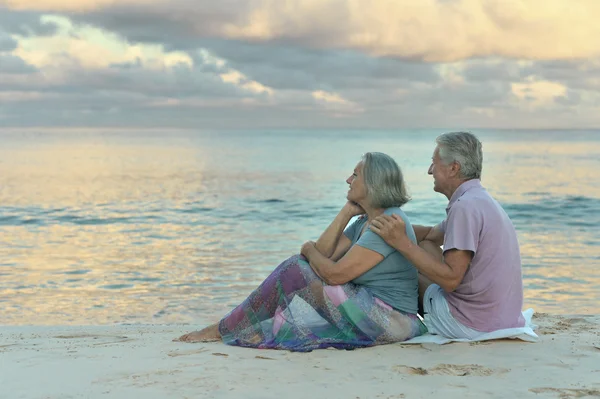 Äldre par sitter på stranden — Stockfoto