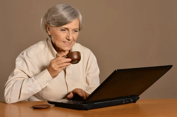 Old woman with  laptop and coffee — Stock Photo, Image