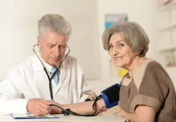 Médecin âgé mesurant la pression artérielle — Photo