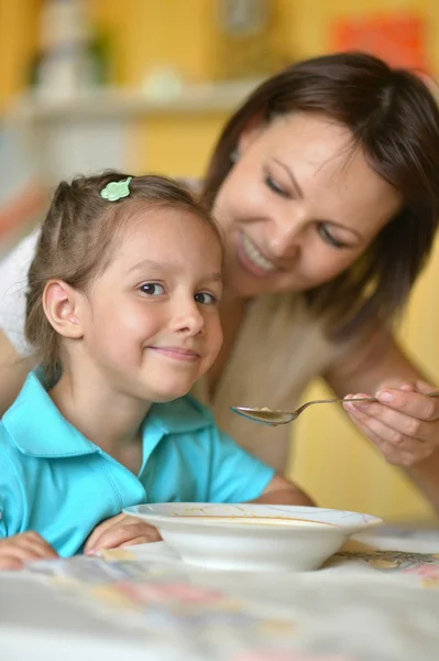 Мать кормит супом дочь — стоковое фото