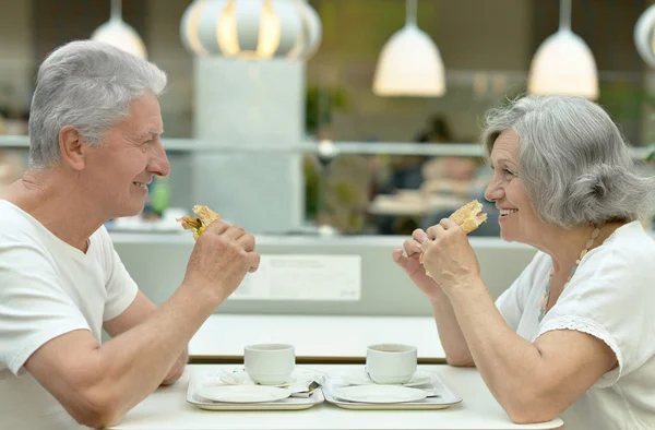 Bejaarde echtpaar eten van broodjes — Stockfoto