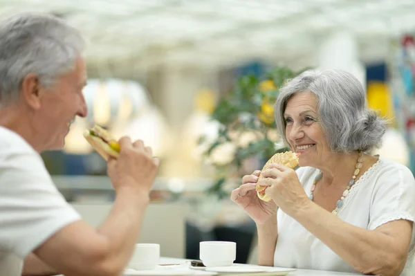 Bejaarde echtpaar eten van broodjes — Stockfoto