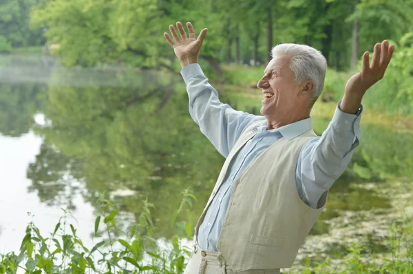 Hombre viejo sonriente cerca del lago —  Fotos de Stock