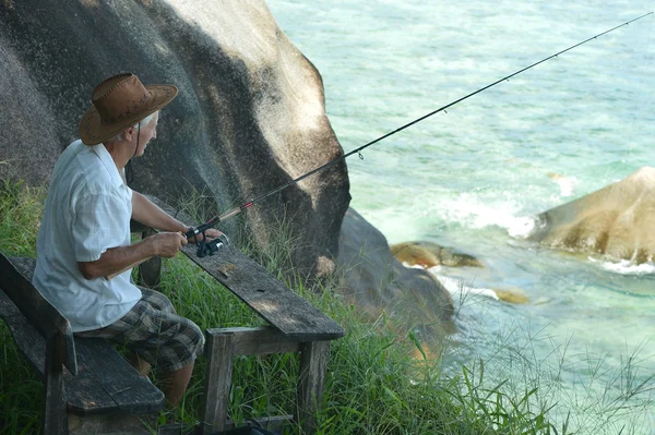 Пожилой человек рыбачит в море — стоковое фото