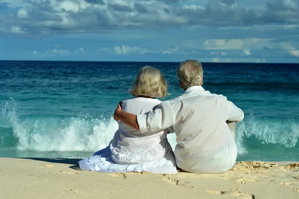 Couple âgé assis sur le rivage — Photo