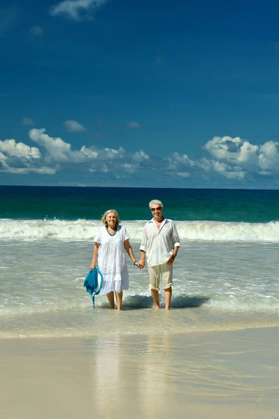 Pareja mayor caminando a orillas del mar — Foto de Stock