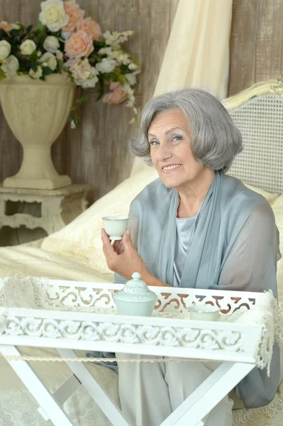 Пожилая женщина на кровати с чаем — стоковое фото
