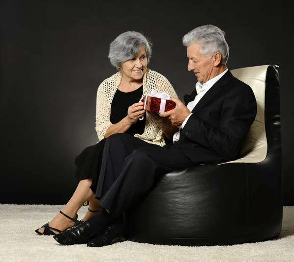 Pareja mayor en sillón con regalo — Foto de Stock