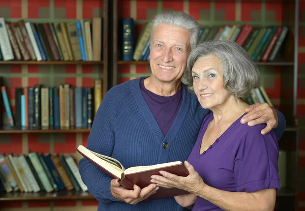 Coppia anziana oltre scaffali libro — Foto Stock