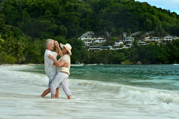 Elderly couple walking along  seashore — Stock Photo, Image