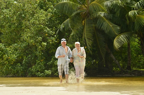 Elderly couple running  on beach — Stock Photo, Image