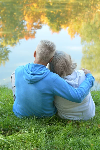 Senior koppel zitten in de buurt van lake — Stockfoto