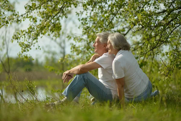 Senior koppel zitten in de buurt van lake — Stockfoto