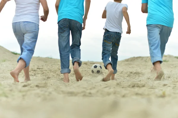 Familj spelar fotboll på en strand — Stockfoto