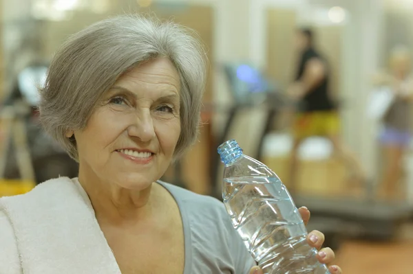 Donna anziana che beve acqua in palestra — Foto Stock