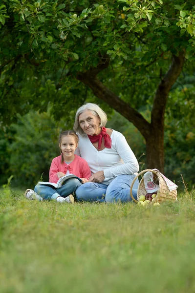 Liten flicka med mormor och boken — Stockfoto