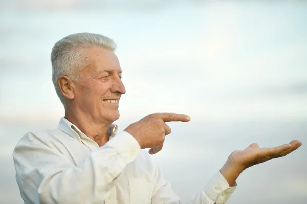 Пожилой человек, указывающий на фоне неба — стоковое фото