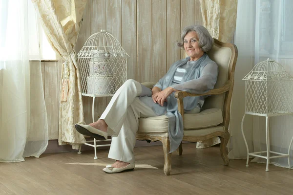 Elderly woman on chair in vintage room — Stock Photo, Image