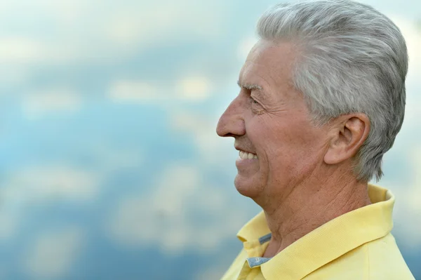 Hymyilevä iäkäs mies lähellä järveä — kuvapankkivalokuva