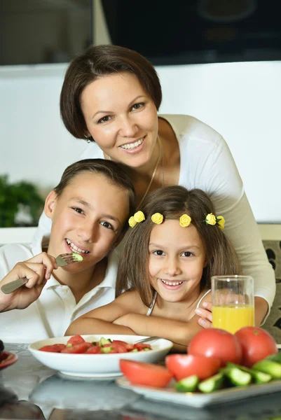 Mother with kids eating at table — Stock Photo, Image