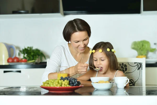Маленькая девочка с матерью ест — стоковое фото