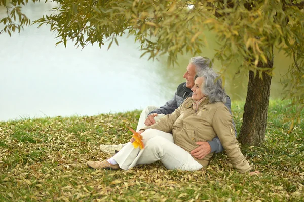 Casal sênior sentado perto do lago — Fotografia de Stock