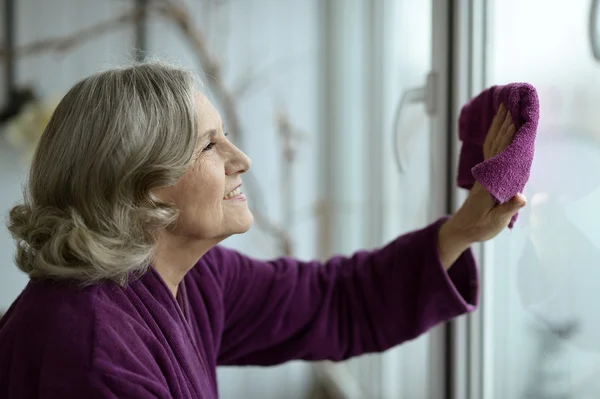 Seniorin putzt Fenster — Stockfoto