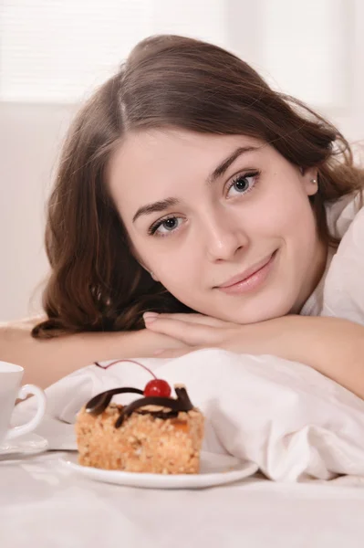 Mooie vrouw in bed met taart — Stockfoto