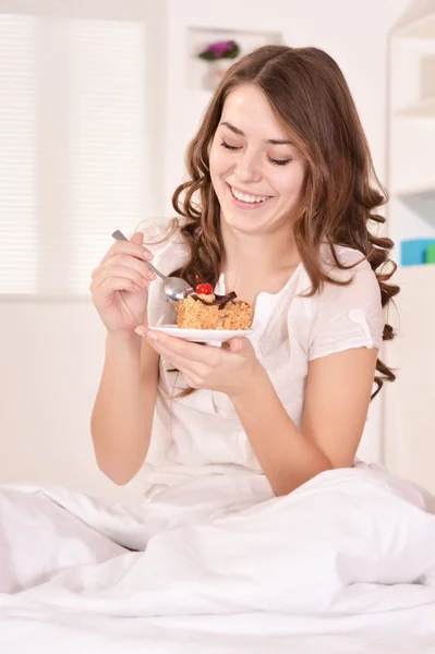 Beautiful woman in bed with cake — Stock Photo, Image