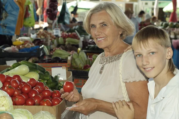 Mujer mayor con chico en el mercado — Foto de Stock