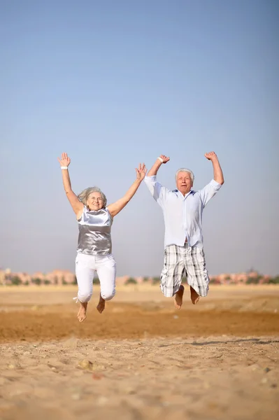 Ältere Paare springen am Strand — Stockfoto