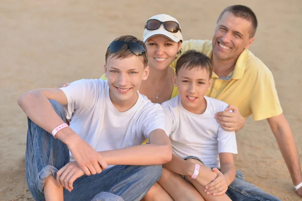 Щаслива сім'я сидить на піску — стокове фото
