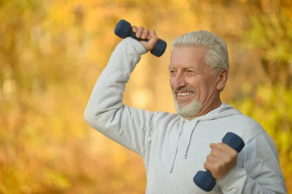 Idős ember gyakorolja a súlyzó — Stock Fotó