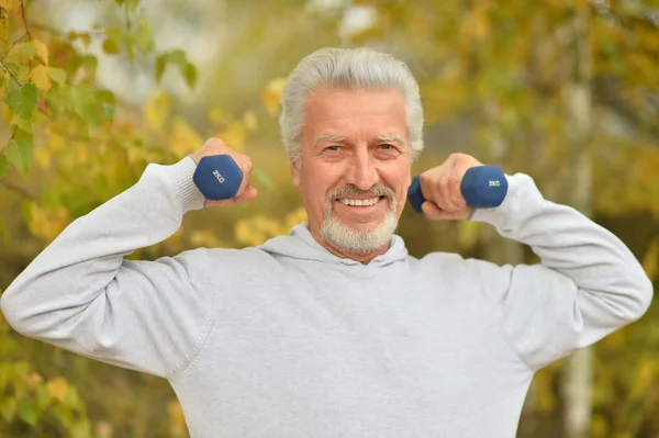 Elderly man exercising with dumbbells — Stock Photo, Image