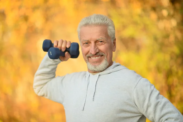 Elderly man exercising with dumbbells — Stock Photo, Image