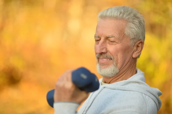 Elderly man exercising with dumbbells — Stock Photo, Image